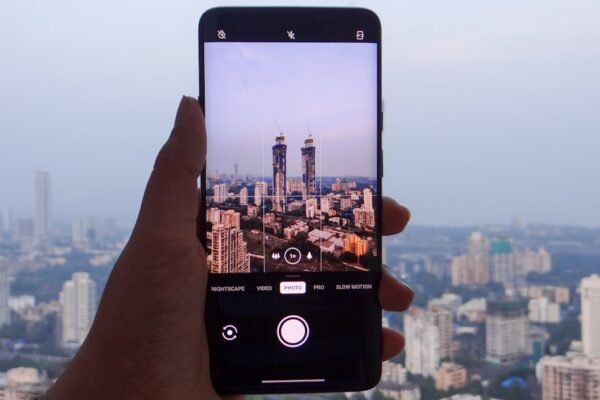 A hand holding a smartphone with Mumbai city skyline in the background, representing India smartphone market